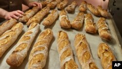 FILE - Baguettes are seen as they come out of the oven of the bakery La Parisienne in Paris, Friday, March 18, 2016.