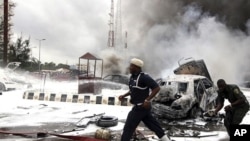 Members of emergency services work at the scene of an explosion at a police station after a suspected suicide bomber was killed and many vehicles were destroyed in Abuja, June 16, 2011