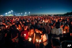 FILE - People attend a candlelight vigil for the victims of the shooting at Marjory Stoneman Douglas High School, in Parkland, Florida.