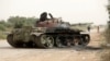 FILE - Members of Libyan internationally recognized government forces walk near a damaged tank belonging to Eastern forces in Al Hira area, south western Tripoli, Libya, April 23, 2019.