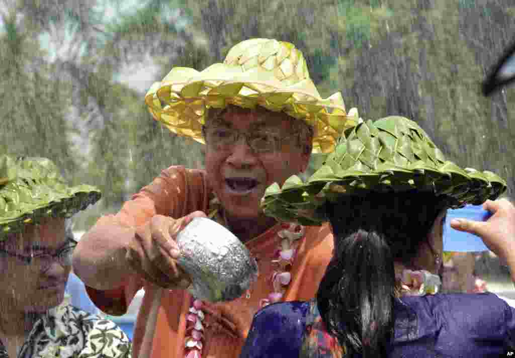 Presiden Myanmar (tengah) memercikkan air kepada seorang penampil dalam upacara yang menandai festival air tahunan di negara itu di Istana Presiden di Naypyitaw (12/4). (AP/Aung Shine Oo)