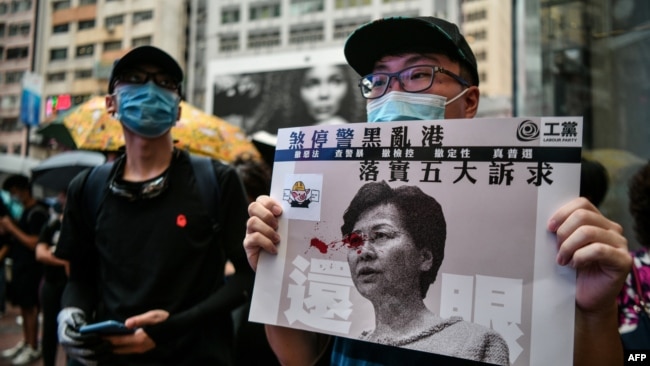A protester displays a poster bearing an image of Hong Kong Chief Executive Carrie Lam in the popular shopping district of Causeway Bay in Hong Kong on August 31, 2019. 
