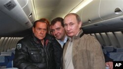 ປະທານາທິບໍດີ Dmitry Medvedev (ເຄິ່ງກາງ) ທ່ານນາຍົກ Vladimir Putin (ຂວາ) ທ່ານນາຍົກລັດຖະ ມົນຕີອີຕາລີ Silvio Berlusconi (ຊ້າຍ) ພາກັນຖ່າຍຮູບຮ່ວມກັນໃນຂະນະທີ່ໄປ ກວດເບິ່ງເຮືອບິນໂດຍສານ ໃໝ່ Sukhoi Superjet 100, ທີູ່ຄຸ້ມບ້ານພັກ Sochi ແຄມທີ່ທະເລດຳໃນພາກ ໃຕ້ຂອງຣັດເຊຍໃນ