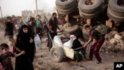 FILE - An elderly woman and a child are pulled on a cart as civilians flee heavy fighting between Islamic State militants and Iraqi special forces in western Mosul, Iraq, May 10, 2017.