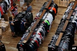 People try garments at a retail and wholesale clothing mall in Beijing, July 16, 2018. China's economic growth slowed in the quarter ending in June, adding to challenges for Beijing amid a mounting tariff battle with Washington.