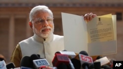 Thủ tướng đắc cử của Ấn Độ và lãnh đạo Đảng BJP thân Ấn Độ Giáo Narendra Modi cầm lá thư Tổng thống mời ông thành lập chính phủ mới ở bên ngoài Dinh Tổng thống tại New Delhi, ngày 20/5/2014.