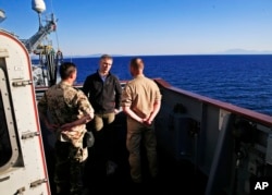 NATO Secretary-General Jens Stoltenberg, center, talks with crew members of the NATO German warship FGS Bonn, on patrol in the Aegean Sea, off the Turkish coast, during a visit, April 21, 2016.