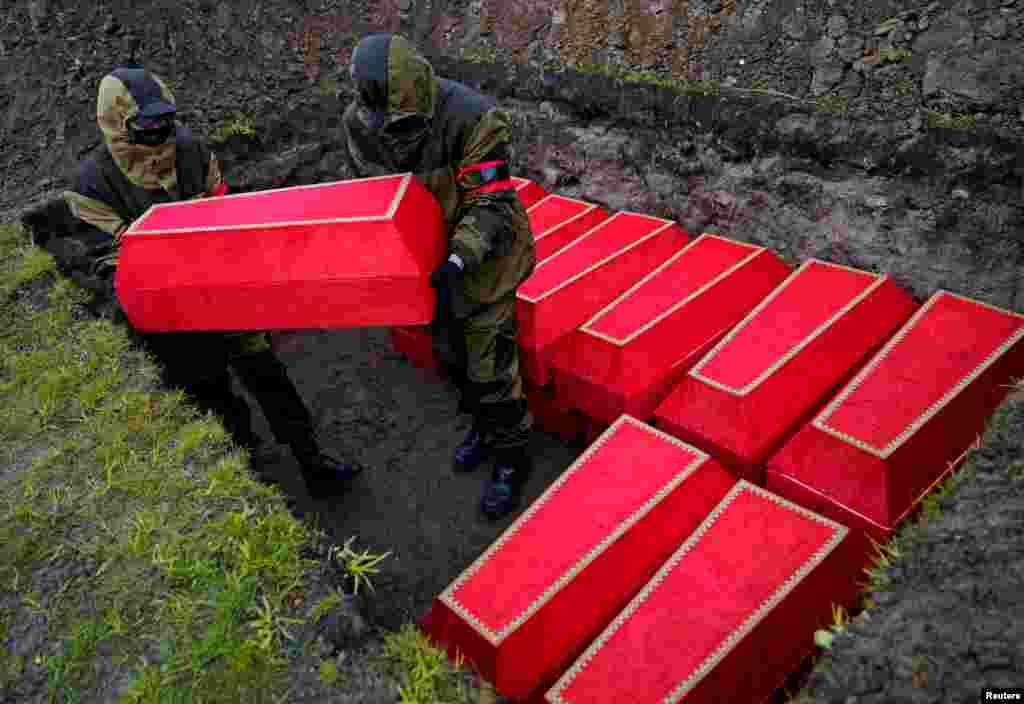 Men place coffins with the remains of Red Army soldiers killed in World War II in a grave during a reburial ceremony ahead of Victory Day celebrations in Kaliningrad, Russia.