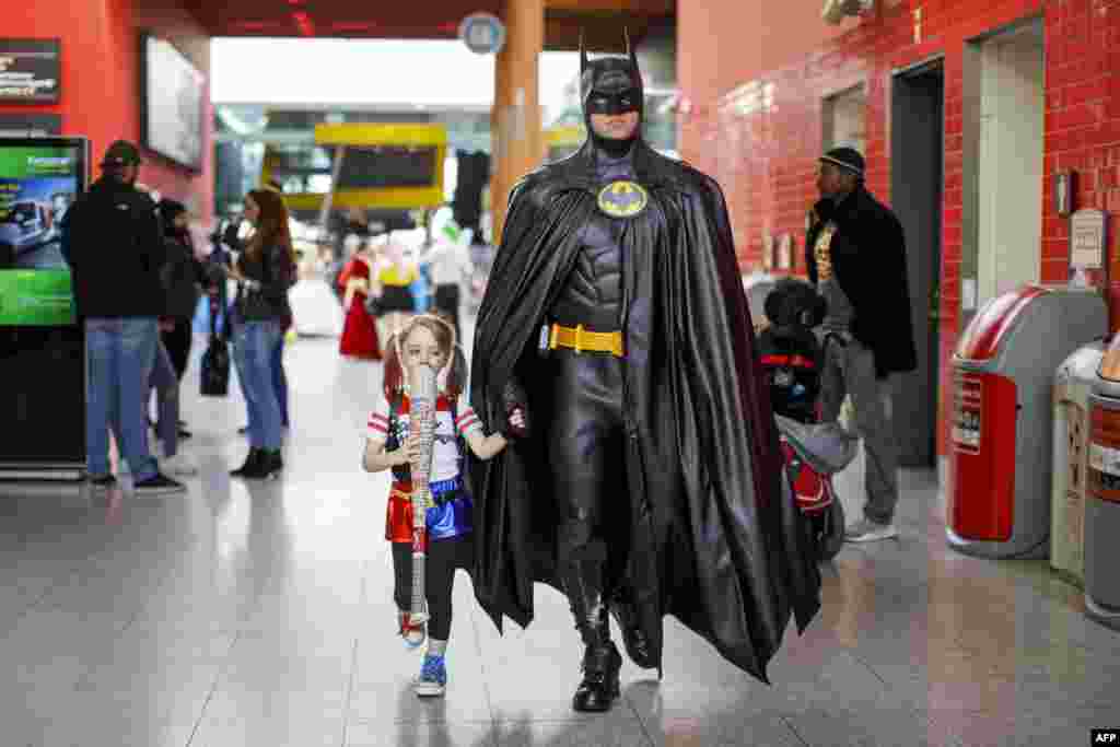 A father dressed as Batman takes her daughter dressed as Harley Quinn to the MCM Comic Con at ExCeL exhibition center in London.