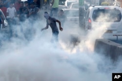 23일 예루살렘과 서안지구 라말라를 잇는 검문소에서 팔레스타인 시위대가 이스라엘 진압병력이 터뜨린 최루가스 속에 서있다.