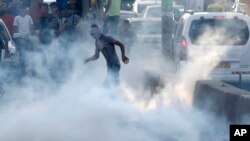 A Palestinian protester stands in tear gas during clashes near the Qalandia checkpoint between Jerusalem and the West Bank city of Ramallah, Sunday, July 23, 2017. Israel's minister of public security said Sunday that metal detectors set at the entrance to a major Jerusalem shrine that angered Palestinians could be removed if police have another way of ensuring security there.