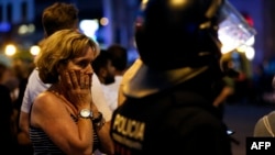 A woman gestures as she is escorted by Spanish policemen outside a cordoned off area, after a van struck members of a crowd on Las Ramblas in Barcelona, Aug. 17, 2017.