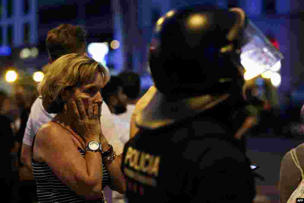 A woman gestures as she is escorted by Spanish policemen outside a cordoned off area, after a van struck members of a crowd on Las Ramblas in Barcelona, Aug. 17, 2017.