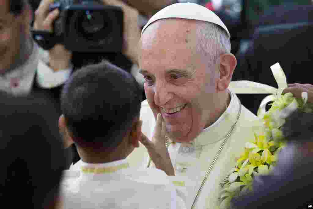 Pope Francis smiles after getting a garland from a child as he arrives for an interfaith meeting in Colombo, Sri Lanka, Tuesday, Jan. 13, 2015.