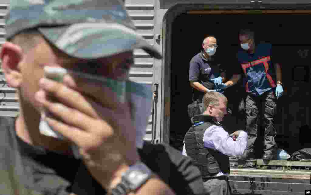 A man covers his face with a rag as deputy head of the OSCE mission to Ukraine Alexander Hug stands outside a refrigerated train as members of Netherlands&#39; National Forensic Investigations Team inspect bodies, seen in plastic bags, Torez, eastern Ukraine, July 21, 2014.