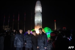 FILE - A group of men stand before an ice sculpture depicting a Hwasong-15 intercontinental ballistic missile at the Pyongyang Ice Sculpture Festival in Pyongyang on Dec. 31, 2017.