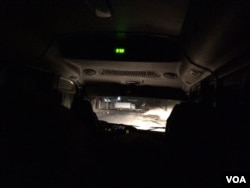 A view from inside the tour bus as it approaches a roadblock consisting of a white truck and large rocks in Gressiers. (S. Lemaire/VOA)