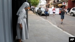 FILE - A nun looks out as the the annual LGBT parade files past, in Asuncion, Paraguay, Sept. 30, 2017. 