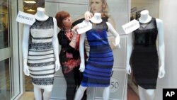 Shop manager Debbie Armstrong adjusts a two tone dress in a window display of a shop in Lichfield, England, Friday Feb. .27, 2015.