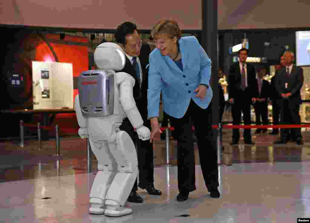 Kanselir Jerman Angela Merkel (kanan), didampingi oleh Mamoru Mori, direktur eksekutif museum dan mantan astronot, memperhatikan &quot;Asimo&quot;, robot humanoid bi-ped yang dikembangkan oleh Honda Motor Co., ketika berkunjung ke Miraikan (Museum Nasional Sains dan Inovasi) di Tokyo, Jepang.