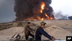 Dua pemuda Irak naik sepeda dekat sumur minyak yang dibakar ISIS di Qayyara, sekitar 50 kilometer dari selatan Mosul, Irak (23/10). 