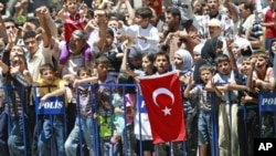 Syrian refugees shout slogans as they protest against Syrian President Bashar al-Assad at a refugee camp in the Turkish border town of Yayladagi in Hatay province, July 1, 2011