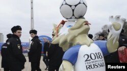 Police officers walk past the official mascot for the 2018 FIFA World Cup Russia, Zabivaka, during the opening of a soccer park in Rostov-on-Don, Russia, March 31, 2018