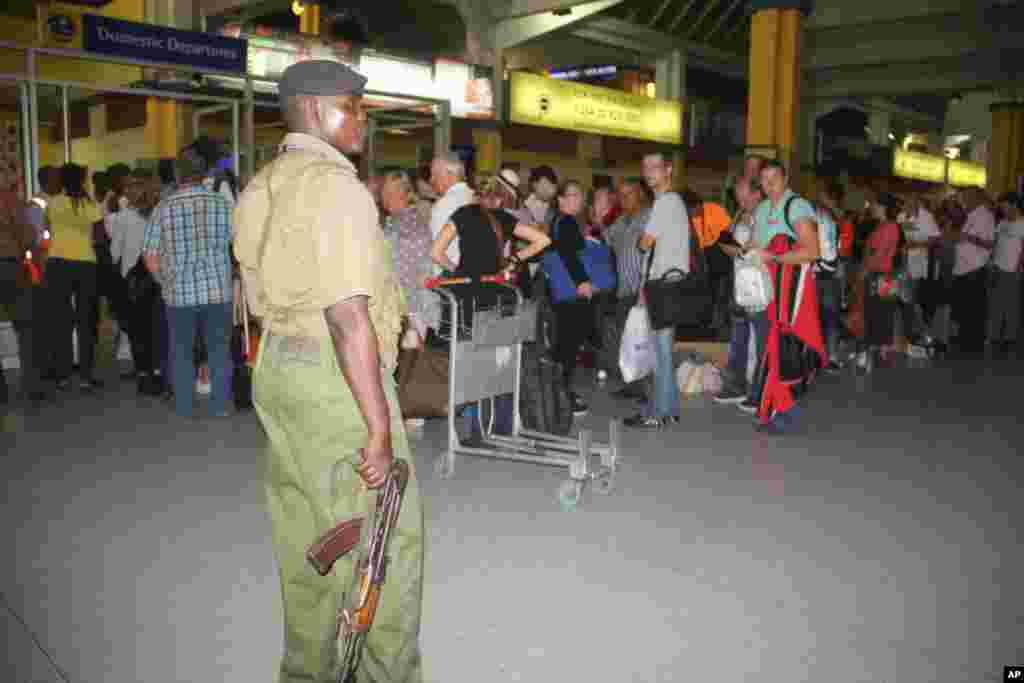 Afisa wa polisi wa Kenya atizama kwa makini wakati abiria wa ndege ya Air France wakipiti kituo cha ukaguzi kwenye uwanja wa ndege wa Moi mjini Mombasa Kenya, Jumapili, Dec. 20, 2015