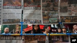 Visitors view the latest newspaper coverage of clashes between protesters and police at a sit-in protest in Hong Kong, Sept. 29, 2014. 