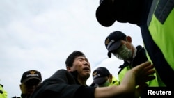 A family member of a passenger missing after the South Korean ferry "Sewol" capsized is blocked by police during a protest in Jindo calling for a meeting with President Park Geun-hye and demanding the search and rescue operation be speeded up, April 20, 2014.
