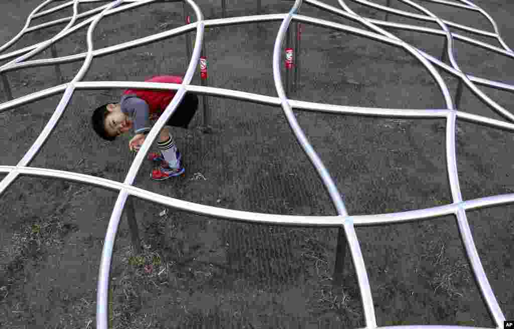 A boy plays under a jungle gym at a park in Tokyo's Roppongi district.