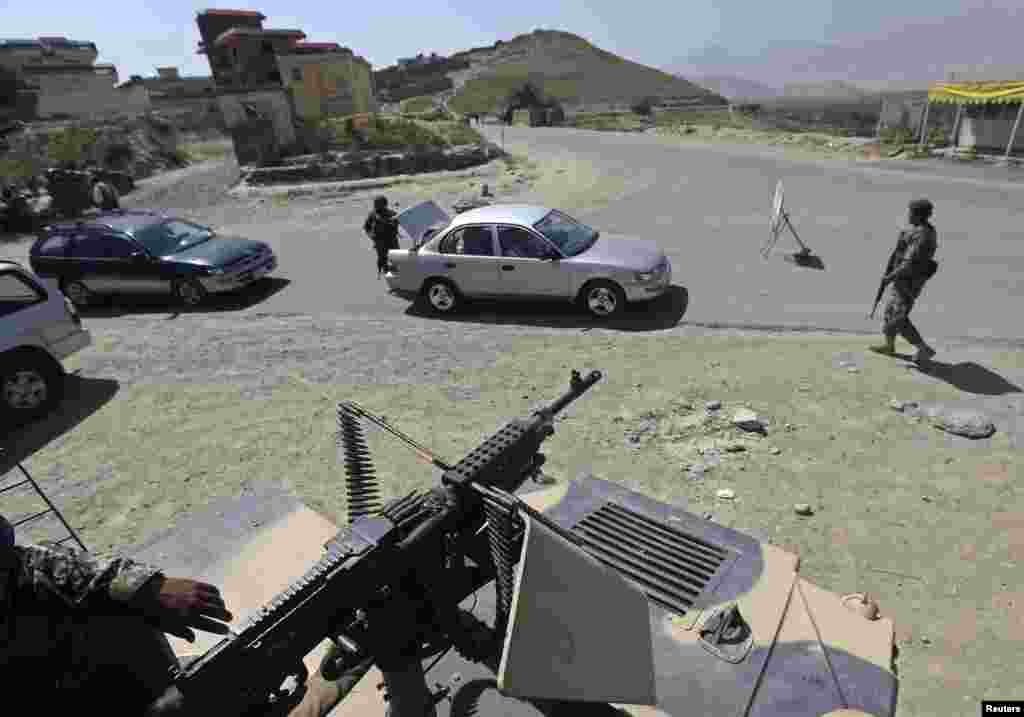 Afghan National Army (ANA) soldiers inspect a car at a check point near the British-run military training academy at Camp Qargha, in Kabul, Aug. 6, 2014.