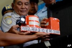 FILE - Head of Indonesian National Transportation Safety Committee Tatang Kurniadi, center, shows the cockpit voice recorder from AirAsia Flight 8501 during a press conference in Pangkalan Bun, Central Borneo, Indonesia.