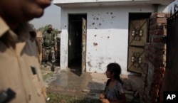 Indian security personnel inspect a house allegedly damaged by from gunfire from the Pakistan side of the border, at a residential area near the international border at Bidipur, in Ranbir Singh Pura, India, Oct. 22, 2016.