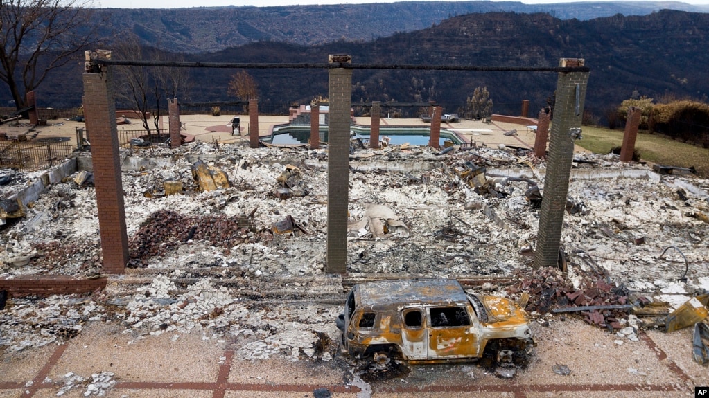 FILE - A vehicle rests in front of a home leveled by the Camp Fire in Paradise, Calif., Dec. 3, 2018. Authorities estimate it will cost at least $3 billion to clear debris of 19,000 homes destroyed by California wildfires last month.