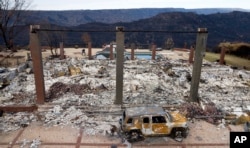 FILE - A vehicle rests in front of a home leveled by the Camp Fire in Paradise, Calif., Dec. 3, 2018.