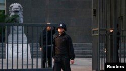 Security personnel stand guard outside as Chinese human rights lawyer Ding Jiaxi stands trial at a court in Haidian District, Beijing, April 8, 2014.