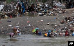 Residents wash clothes recovered from their flood damaged houses on the banks of the Adyar River in Chennai, India, Dec. 6, 2015.