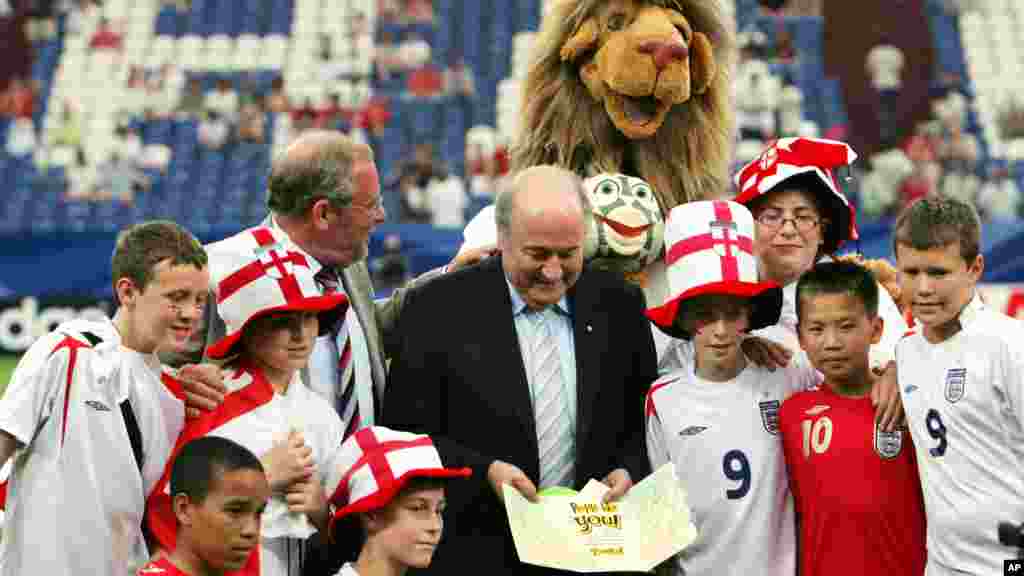 FIFA President Sepp Blatter holds a "thank you" cards given to him by English school children, seen around him as they stand inside the World Cup stadium in Gelsenkirchen, Germany, Saturday, July 1, 2006 before the England vs. Portugal World Cup, quarterf