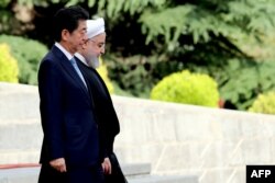 Iranian President Hassan Rouhani, right, welcomes Japanese Prime Minister Shinzo Abe at the Saadabad Palace in the capital Tehran, June 12, 2019.