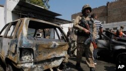 A Pakistani soldier walks past damaged vehicles at the site of a deadly suicide bombing in Charsadda, Pakistan, Monday, March 7, 2016. The suicide bomber attacked the entrance to a court in the town of Shabqadar northwestern Pakistan on Monday, killing many people, police said. (AP Photo/Mohammad Sajjad)