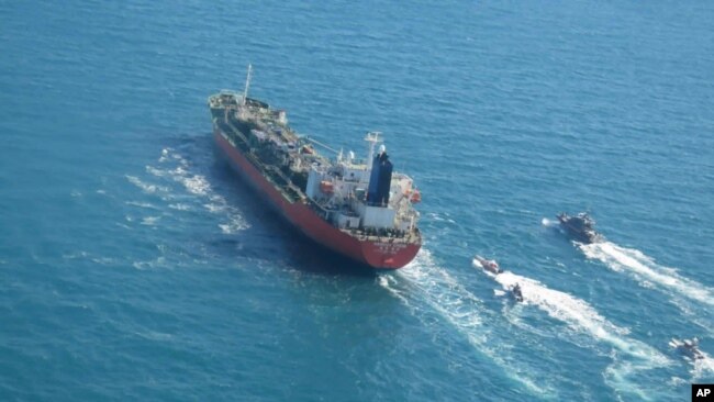 In this photo released Monday, Jan. 4, 2021, by Tasnim News Agency, a seized South Korean-flagged tanker is escorted by Iranian Revolutionary Guard boats on the Persian Gulf. (Tasnim News Agency via AP)