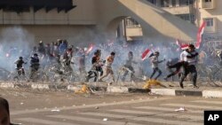 Protesters run from tear gas fired by security forces, during a demonstration by followers of Iraq's influential Shi'ite cleric Muqtada al-Sadr, in Baghdad, Iraq, Feb. 11, 2017.