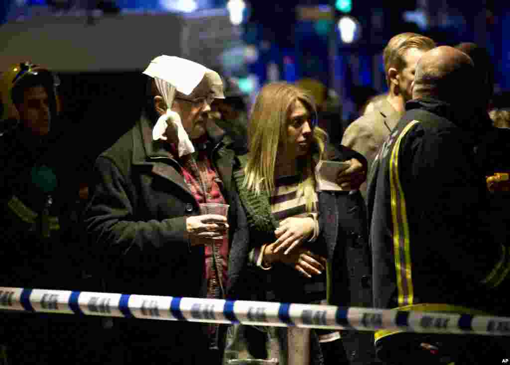 A bandaged man comforts a woman after part of the ceiling collapsed at the Apollo Theatre, Shaftesbury Avenue, London, Dec. 19, 2013.