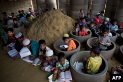 Rohingya refugee children attend recitation classes of the holy Quran in a newly opened madrasa, or religious school, amid material stocked for constructing latrines in Balukhali refugee camp, Bangladesh, Oct. 30, 2017.