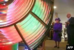 FILE - Britain's Queen Elizabeth II looks at an optic from the decommissioned Orfordness Lighthouse, built by Chance Brothers of Smethwick and installed in Suffolk in 1913, during a visit to the International Maritime Organization in London, March 6, 2018