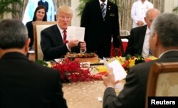 President Trump holds up the menu as he attends a lunch with Singapore's Prime Minister Lee Hsien Loong at the Istana in Singapore, June 11, 2018. (Ministry of Communications and Information, Singapore/Handout via Reuters)