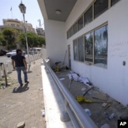 A man checks the damaged US embassy after pro-government protesters attacked the embassy compound in Damascus, Syria, July 11, 2011