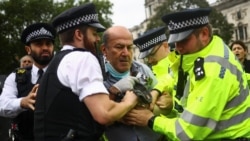 Policija odvodi demonstranta za koga se smatra da je istrčao pred vozilo u kome se nalazio britanski premijer