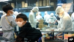 戴口罩孩童在台北一家鼎泰豐餐廳外觀看師傅包小籠包。(2020年3月7日)